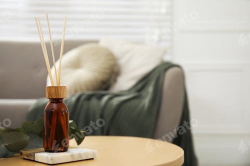 Preview: Reed diffuser with eucalyptus on wooden table in living room. Space for text