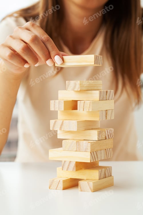 Preview: Hand of a young business woman To play wood block game with strategy and planning business project