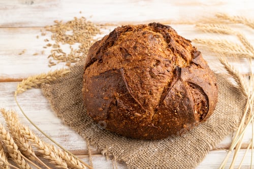 Preview: Fresh homemade golden grain bread with ears on white, side view, close up.