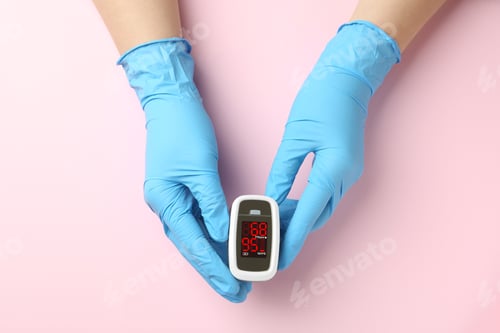 Preview: Doctor in latex gloves holding fingertip pulse oximeter on pink background, top view
