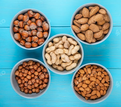 Preview: top view of mixed nuts in shell and without shell in bowls almond hazelnuts and peanuts