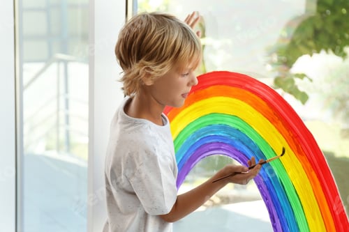 Preview: Little boy drawing rainbow on window. Stay at home concept