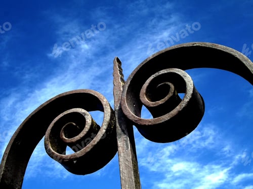 Preview: Ironwork Spiral Design Against a Cloudy Blue Sky