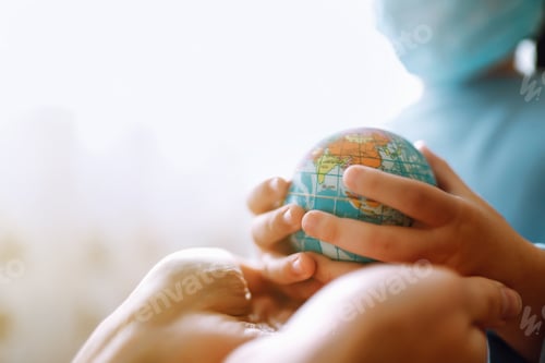 Preview: Child in protective sterile medical mask holding a world globe. Save planet. Planet sterilization.