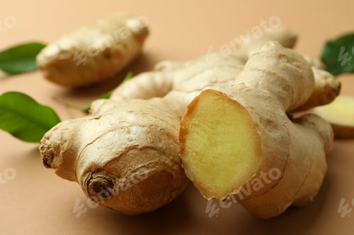 Preview: Fresh ginger and green leaves on light pale brown background, closeup