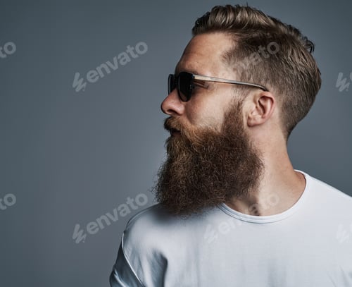 Preview: Cool young man with a beard wearing sunglasses looking sideways