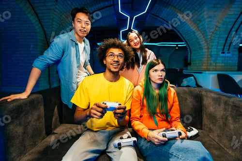 Preview: Multiethnic group of young friends playing videogames at home