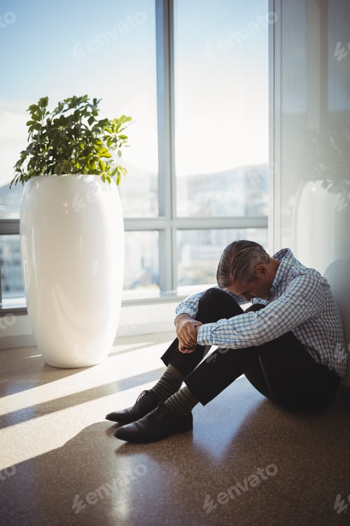 Preview: Sad executive sitting on floor