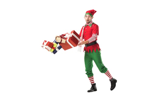 Preview: surprised man in christmas elf costume accidentally dropping pile of presents isolated on white