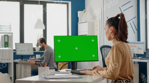Preview: Woman working with isolated green screen on monitor at desk