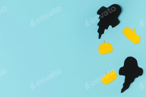 Preview: Halloween. Black ghosts and yellow pumpkins decorations on blue background flat lay. Happy Halloween