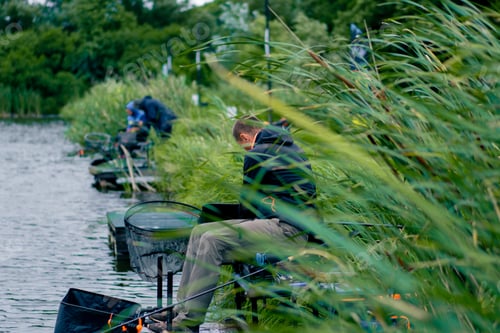 Preview: Fisherman with fishing rod or spinning and professional tools sitting on the river bank
