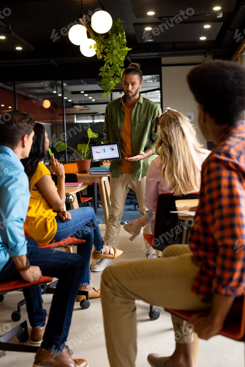 Preview: Caucasian casual businessman presenting to diverse colleagues using tablet in office