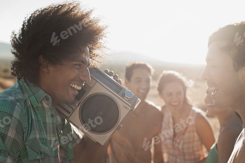 Preview: Group of young people, men and women walking on the open road with a boombox.