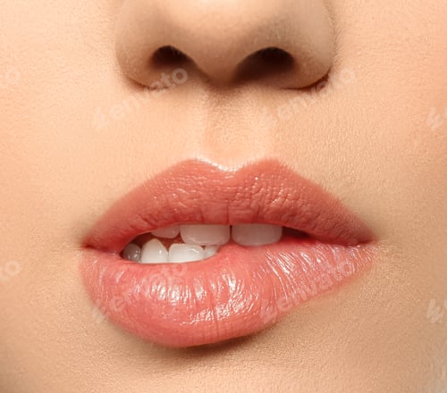 Preview: Beautiful young woman biting lip on grey background, closeup