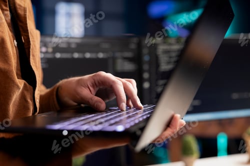 Preview: Computer scientist working from home using laptop checking code displayed on PC