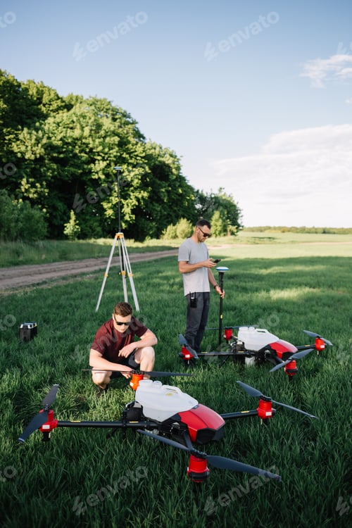 Preview: A drone pilot configuring his drone in a field with and irrigation system before flying.