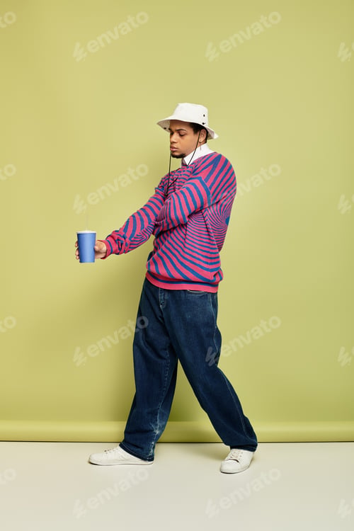 Preview: Trendy young man enjoys a refreshing drink in a stylish abstract sweatshirt