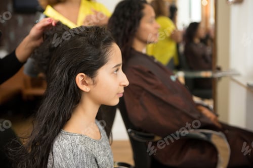 Preview: A young girl getting her hair done at a salon, with another customer in the background.