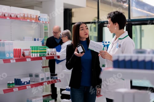 Preview: Pharmaceutical assistant and aisan woman discussing vitamin complex components