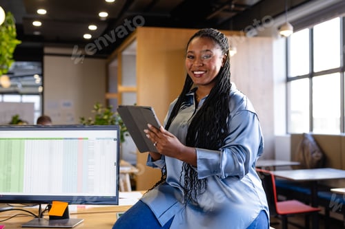 Preview: Portrait of happy plus size african american casual businesswoman using tablet in office