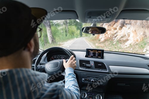 Preview: Man driving car while being on a day road trip.