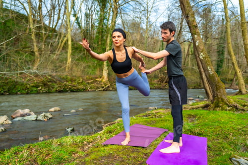 Preview: Yoga instructors practicing balancing pose by the river