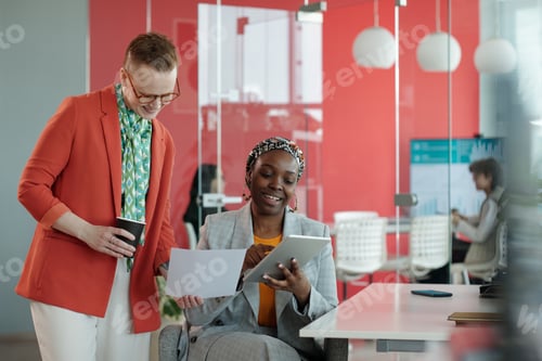 Preview: Female Colleagues Using Tablet and Reviewing Documents in Office