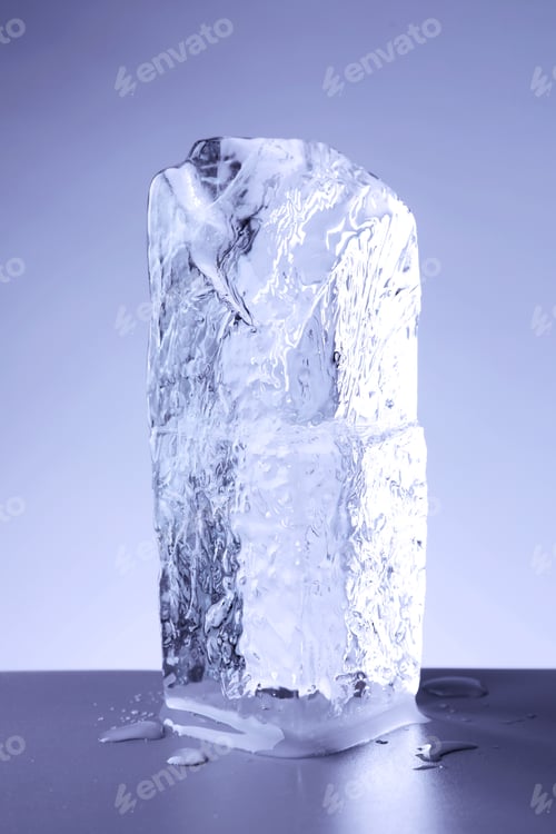 Preview: Piece of clear ice and water drops on light blue table