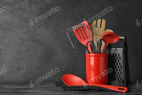 Preview: Holder with kitchen utensils on grey table against dark background. Space for text