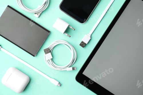 Preview: USB charge cables, power adapter and gadgets on light blue background, flat lay. Modern technology