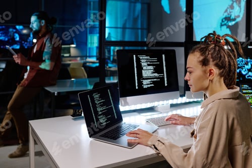Preview: Serious female programmer with dreadlocks decoding data on laptop screen