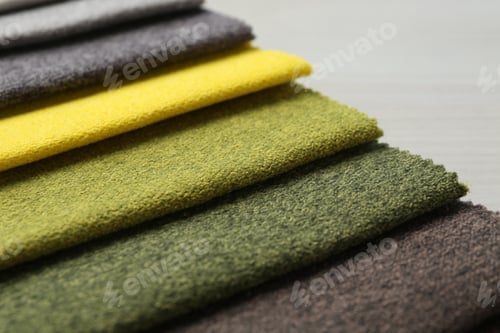 Preview: Samples of different fabrics on light wooden table, closeup