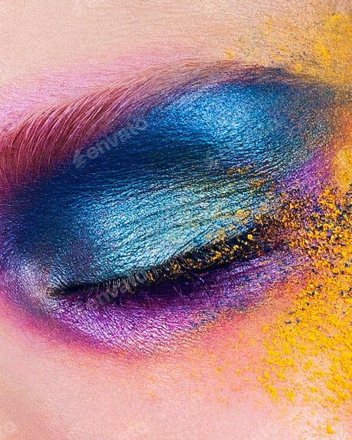 Preview: Studio shot of young woman's eye with multi coloured powder eye shadow, close up