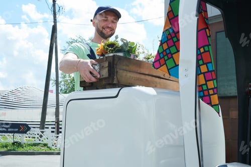 Preview: Man holding box with flowers in sunny day