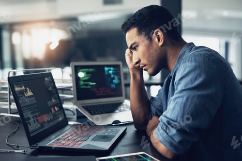 Preview: Shot of a young man suffering from a headache while using a laptop in a modern office