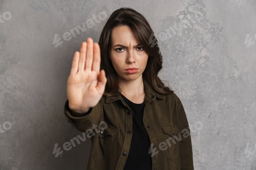 Preview: Displeased beautiful girl looking and showing stop gesture at camera
