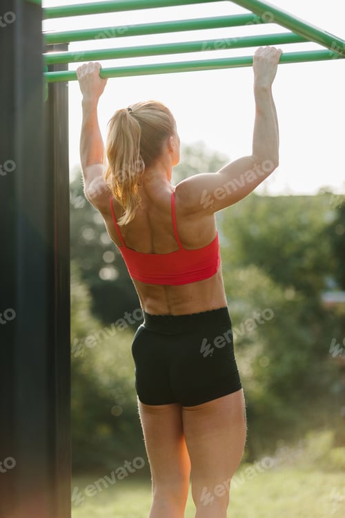 Preview: Woman exercising on monkey bars outdoors training strength