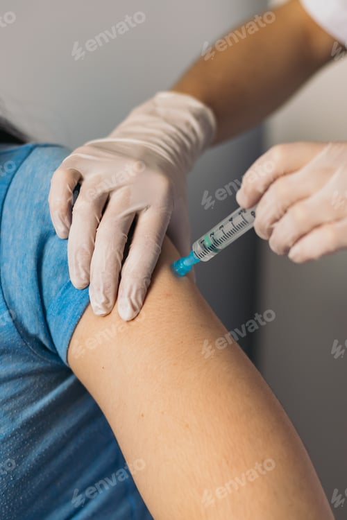 Preview: Doctor hands injecting vaccine in the arm of a patient.