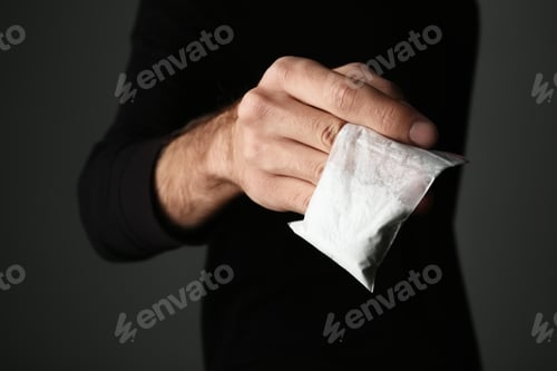 Vista previa: Traficante de drogas con bolsa con cocaína sobre fondo oscuro, primer plano