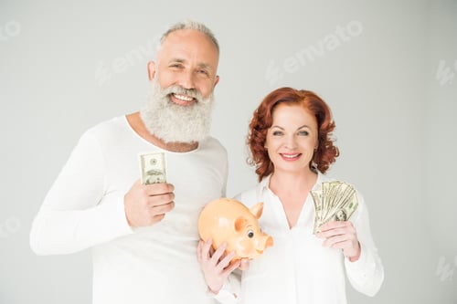Preview: smiling mature couple with dollar banknotes and piggy bank, isolated on white
