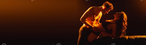 Preview: panoramic concept of muscular man hugging sexy woman in underwear near sofa on black