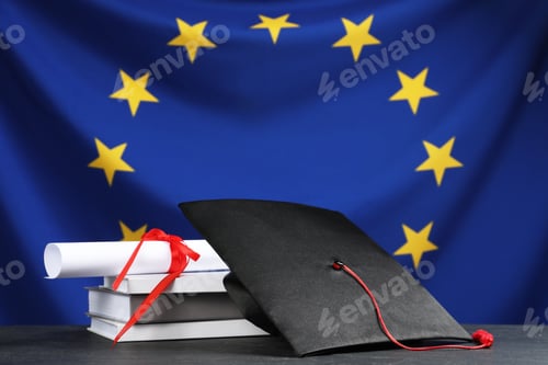 Preview: Graduation cap, diploma and books on black table against flag of European Union