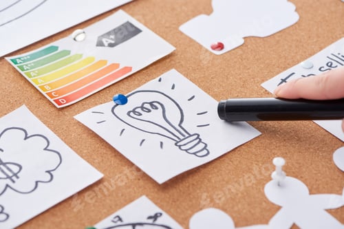 Preview: cropped view of woman pointing with black highlighter on idea drawing pinned on cork board