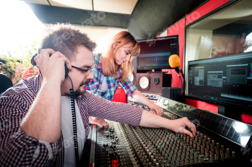 Preview: Music engineer and musician working together in recording studio using mixing desk