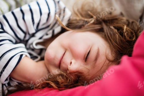 Preview: A small happy girl in striped T-shirt at home sleeping.