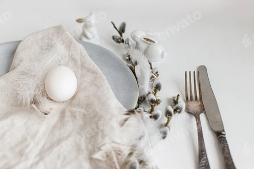 Preview: Stylish Easter table setting. Natural easter egg, willow branches and feathers on modern plate