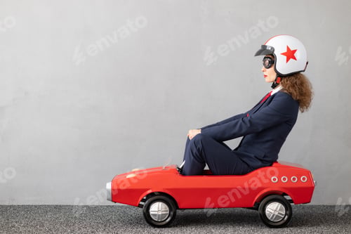 Preview: Successfull businesswoman driving toy car outdoor