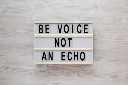 Preview: 'Be voice not an echo' on a lightbox on a white wooden background, top view.