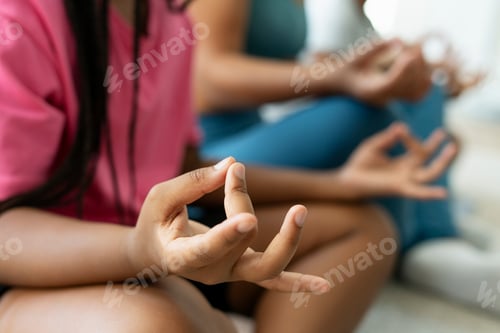 Preview: African American girl doing yoga, sitting in lotus pose, holding hands, selective focus on hands